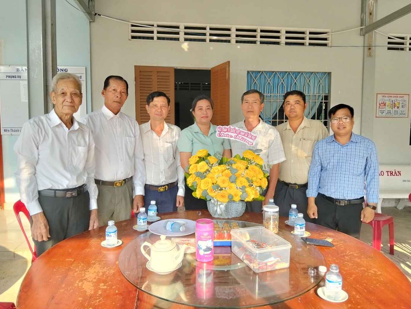 Description: A group of people standing around a table with flowers

AI-generated content may be incorrect.